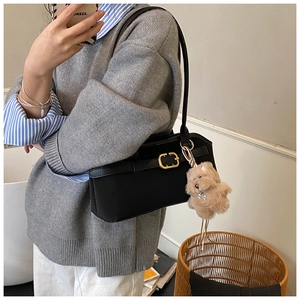 Details der schwarzen matten Ledertasche mit goldener Schnalle und braunem Plüsch-Anhänger