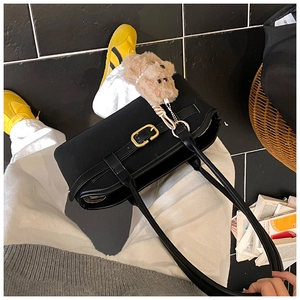 Detail der vintage mattschwarzen Lederschultertasche mit Goldschnalle und Bäranhänger
