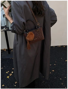 Vue extérieure du sac seau léopard avec pompon et gland sur un manteau en laine