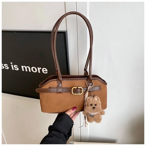 Detail der matten braunen Vintage-Schultertasche mit Lederbesatz und Bärenanhänger