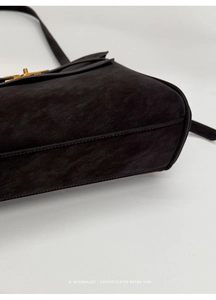 Detailaufnahme des goldenen Drehverschlusses an einer dunkelbraunen matten Vintage-Tasche
