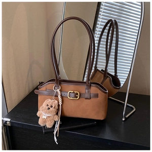 Detailansicht einer braunen Vintage-Tasche mit mattem Finish und kleinem Bären-Anhänger