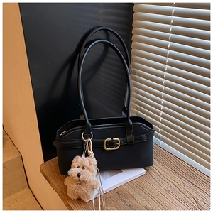 Detail der schwarzen Vintage-Schultertasche mit goldener Schnalle und Plüsch-Hund