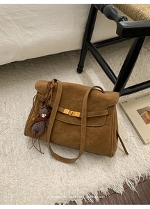 Nahaufnahme der braunen Veloursleder-Tasche mit goldenem Schloss und Bären-Anhänger