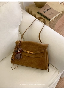 Detail der braunen Vintage-Tasche mit goldenem Drehverschluss und lila Bärenanhänger