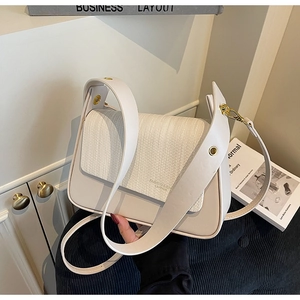 Close-up of cream shoulder bag featuring woven texture flap and gold hardware detail
