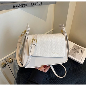 Detail of ivory faux leather handbag showing woven textured flap and gold hardware