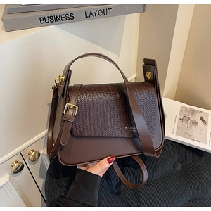 Detail of dark brown shoulder bag with woven V-pattern flap and gold metal buckle