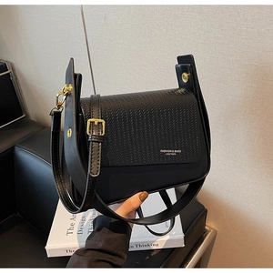 Close-up of black crossbody bag featuring woven leather texture and gold buckle detail