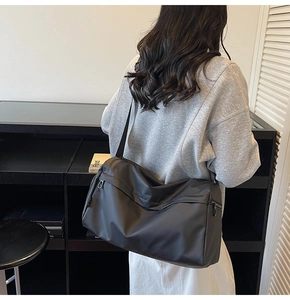 Close-up of black minimalist shoulder bag with adjustable strap shown on a model
