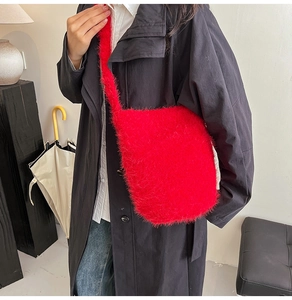 Détail du sac à bandoulière en fausse fourrure rouge avec sangle sur manteau noir