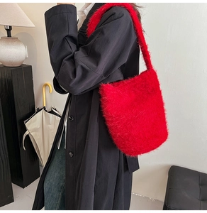 Vue latérale du sac à bandoulière en peluche rouge avec un trench-coat noir élégant