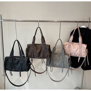 Detailansicht von Retro-Tragetaschen in Schwarz, Braun, Grau und Rosa mit Fransen