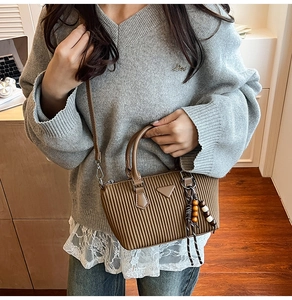 Dettaglio di una borsa a secchiello vintage in pelle marrone con ciondolo stile boho