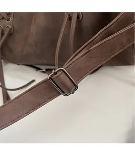 Detail eines verstellbaren Schultergurts und einer Schnalle an einer braunen Wildledertasche