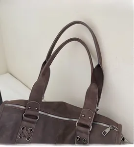 Detail der langlebigen Doppelgriffe und silbernen Metallbeschläge an brauner Hobo-Tasche