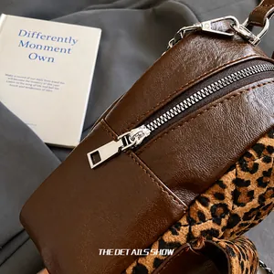 Détail de la fermeture éclair argentée et du tissu léopard sur le sac en cuir brun