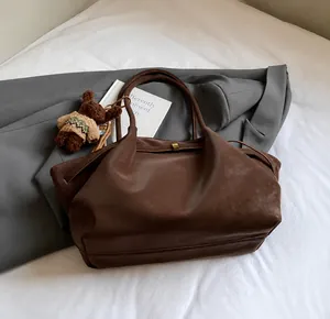 Détail du sac cabas en cuir mat marron foncé avec un pendentif ours en peluche et boucle