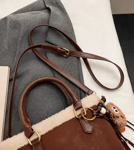 Close-up of brown leather bag with white plush fur trim and beaded pendant
