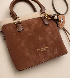 Detail of brown matte handbag with plush cream trim and a cute teddy bear charm