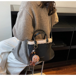 Detail of black leather bucket bag with plush fur trim and cute cookie pendant accessory