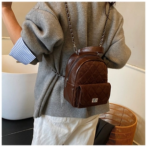 Détail d'un sac à dos matelassé marron avec fermoir rotatif argenté et chaîne métal