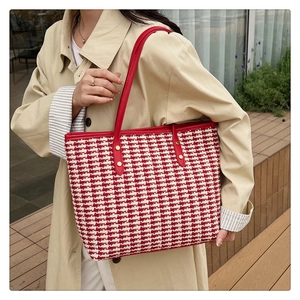 Detail showing the red and white houndstooth woven pattern and gold buckle of a tote bag