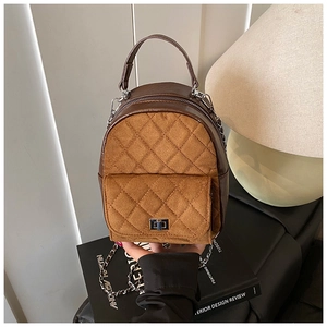 Détail d'un mini sac à dos en cuir matelassé sur un livre avec bandoulière chaîne