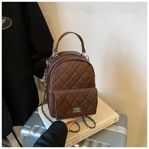 Détail d'un sac à dos matelassé marron foncé avec fermoir rotatif et texture en daim
