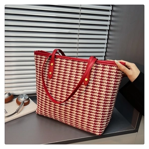 Macro view of red and white woven tote bag with leather handles and gold rivet details