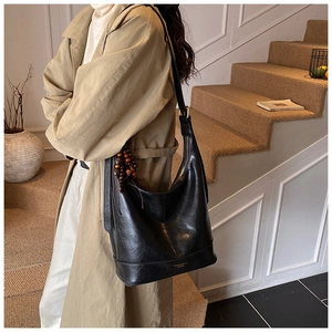 Detalle de bolso tote grande de cuero brillante negro con colgante de cuentas de madera