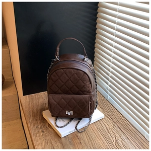 Détail du sac à dos marron matelassé avec fermoir rotatif argenté et bandoulière chaîne