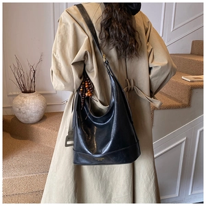 Detalle de bolso hobo de cuero mate negro con adorno de madera y texto dorado