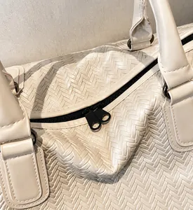 Detail view of woven texture cream travel bag featuring smooth black double metal zippers