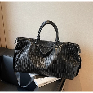 Detail of woven texture black leather travel bag with dual zippers and woven strap