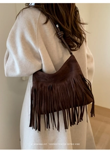 Detail view of dark brown suede fringe bag with bohemian tassels and knotted shoulder strap