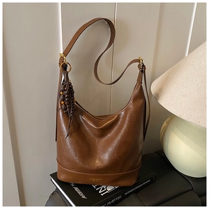 Primer plano del bolso de cuero marrón con borla de madera y hebillas doradas retro