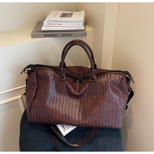 Close-up of dark brown woven leather texture on a premium large capacity travel bag