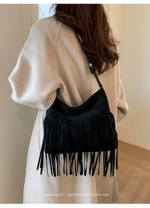 Detail shot of a black minimalist retro tassel shoulder bag worn by a model
