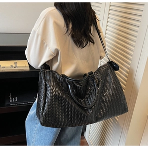 Detail of a large black woven texture tote bag made of premium PU leather for travel