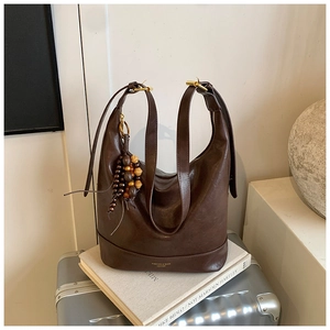 Detalle del bolso tote de cuero marrón vintage con hebilla dorada y colgante de perlas