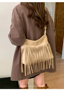 Detail shot of beige suede-like shoulder bag with long bohemian tassels and knotted strap