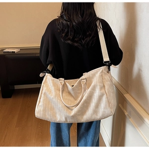 Detail of cream woven tote bag featuring adjustable wide nylon strap and textured finish