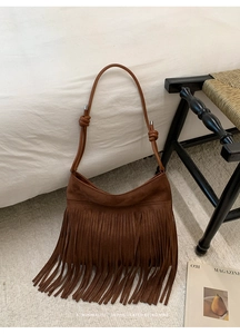 Détail d'un sac à bandoulière en daim marron avec de longues franges et une sangle nouée