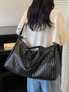 Large black woven leather tote bag with V-pattern weave and adjustable strap for travel