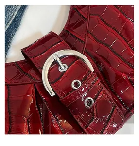 Close-up of dark red crocodile pattern patent leather with silver metal buckle detail