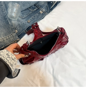 Detailed interior of crocodile pattern burgundy bag with silver rivets and zip pocket