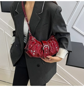 Detail of red crocodile hobo bag with punk rivets and silver metal buckle on model
