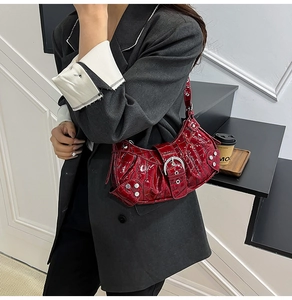 Detail shot of bright red crocodile-pattern patent leather handbag with silver hardware studs