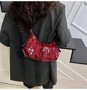 Detail of burgundy crocodile pattern shoulder bag with silver studs and metal buckles